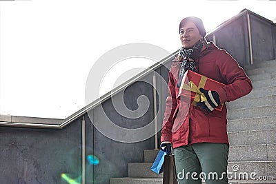 Smiling man holding gifts while moving down steps Stock Photo