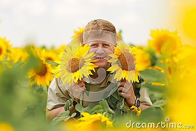 Smiling man holds sunflowers in the middle of sunflower field Stock Photo