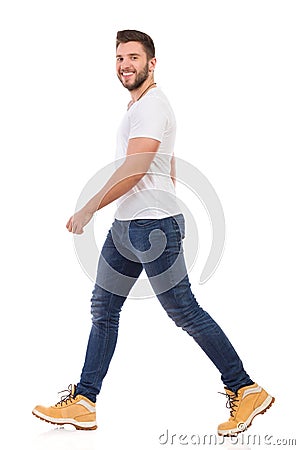 Smiling Man In Jeans And White T-shirt Is Walking Side View Stock Photo