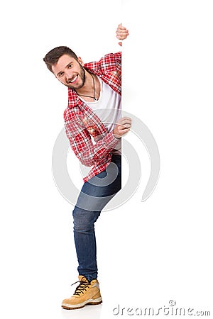 Smiling man jumping out from behind white banner Stock Photo