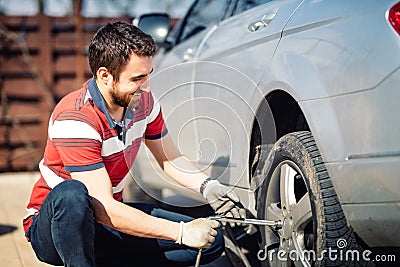 Smiling man and mechanic changing tyres, using jack and wheel wrench Stock Photo