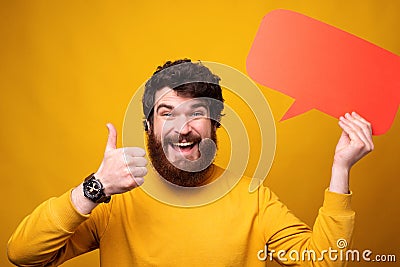 Smiling man is showing thumb up and holding a red spech bubble. Stock Photo