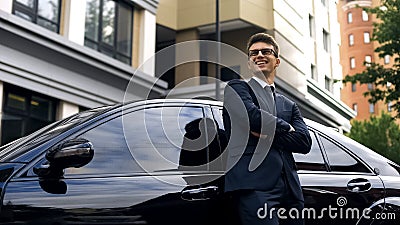 Smiling man standing near premium class car, auto crediting, low interest rate Stock Photo