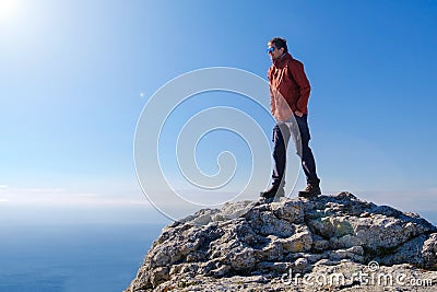 Smiling man in sunglasses standing at the peak of rock mountain Stock Photo