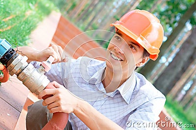 Smiling manual worker repairing pipe Stock Photo