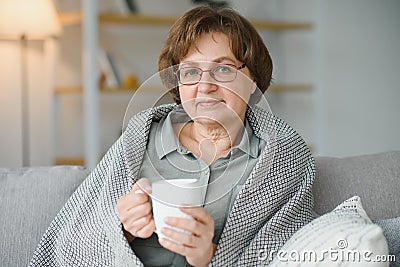 Smiling mature elder 65s woman sitting relaxing with cup of tea, coffee. Senior mid age stylish look woman with Stock Photo