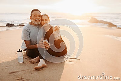 Smiling mature european man hugs woman in sportswear, rest from workout, drink bottle of water Stock Photo