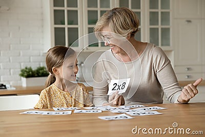 Smiling mature grandmother with little granddaughter learning multiplication table Stock Photo