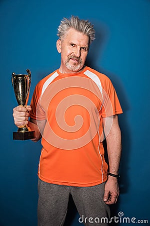 Smiling mature man in sportswear holding trophy cup Stock Photo