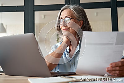 Smiling mature middle aged business woman holding cv searching job online. Stock Photo