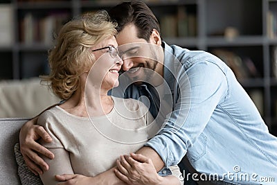 Smiling mature woman and adult son cuddling, enjoying tender moment Stock Photo