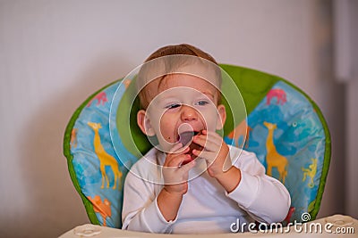 Smiling messy baby likes to eat Stock Photo