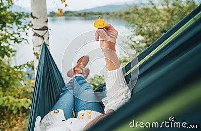 Smiling middle-aged man dressed in warm knitted clothes and jeans lying in the cozy car trunk and enjoying the mountain lake view Stock Photo