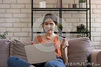 Smiling millennial european female bank client involved in online shopping. Stock Photo