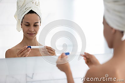 Smiling millennial girl looking at indefinite pregnancy test kit Stock Photo