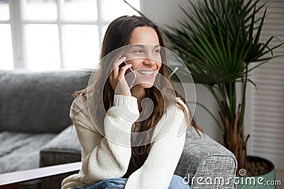 Smiling millennial mestizo woman talking on the phone at home Stock Photo