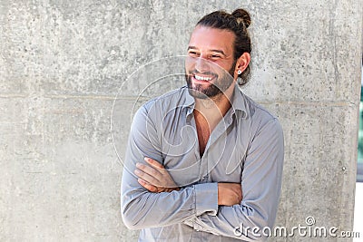 Smiling modern man with beard standing with arms crossed Stock Photo