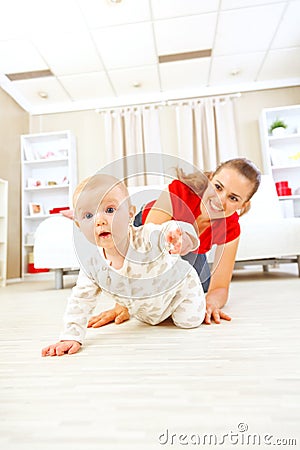 Smiling mommy playing with creeping on floor baby Stock Photo