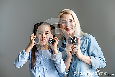 Smiling mommy and preschool daughter make word Mama playing with ABCs, closeup in soft focus of hands holding letters Stock Photo