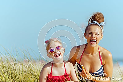 Smiling mother and child use lipstick with spf on seacoast Stock Photo