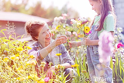 Smiling mother giving flowers to daughter while gardening at farm Stock Photo