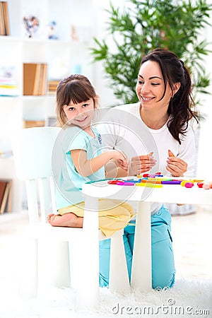 Smiling mother helps a little daughter to sculpt figurines from plasticine. Children`s creativity. Happy family Stock Photo