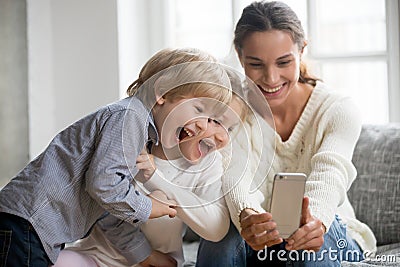 Smiling mother taking selfie with two cute kids on smartphone Stock Photo