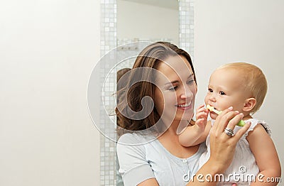 Smiling mother teaching cute baby how to brush teeth with toothbrush Stock Photo