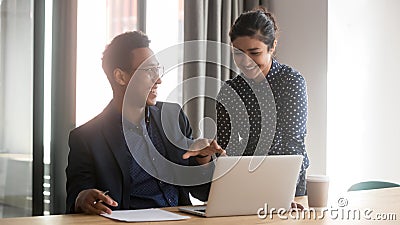 Smiling multiethnic diverse colleagues talk cooperating at laptop Stock Photo