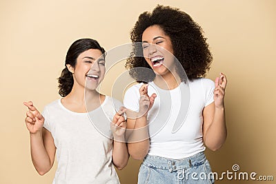 Smiling multiracial girlfriends cross fingers make wish Stock Photo