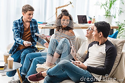 smiling multiethnic teenagers sitting on sofa Stock Photo