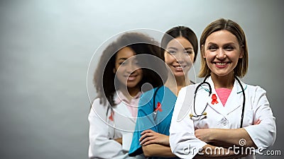 Smiling multiracial doctors with red ribbons, international AIDS awareness sign Stock Photo