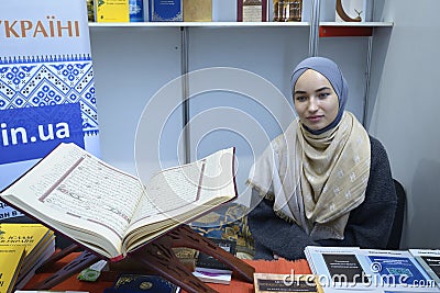 Smiling muslim girl wearing hijab presenting islamic literature in the bookshop, Quran placed on the counter Editorial Stock Photo