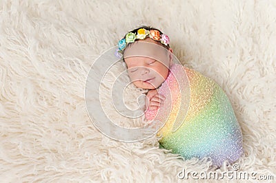 Smiling Newborn Baby Girl Wearing a Rainbow Colored Swaddle Stock Photo