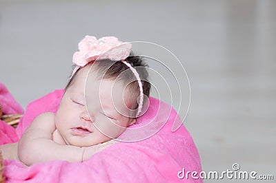 Smiling newborn sleeping in basket with knitted flower on head, baby girl lying on pink blanket, cute child Stock Photo