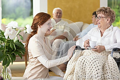Smiling nurse taking care of disabled senior woman in the nursing house Stock Photo