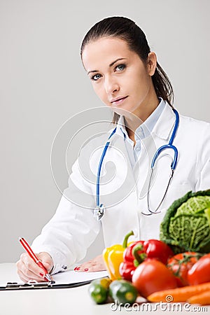 Smiling nutritionist writing medical prescriptions Stock Photo