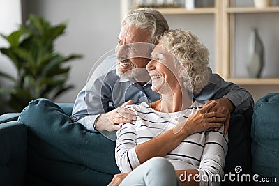 Smiling older couple dreaming together, looking out window Stock Photo