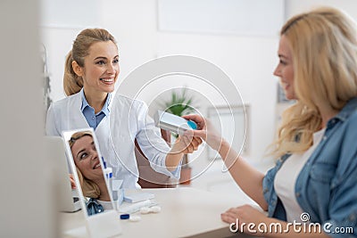 Friendly ophthalmologist in white lab coat prescribing contact lenses for blond lady Stock Photo