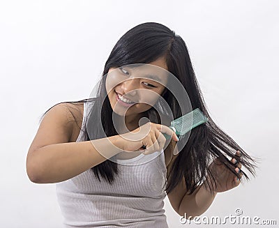 Smiling oriental girl brushing her hair Stock Photo