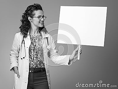 Smiling paediatrician woman looking at placard on Stock Photo