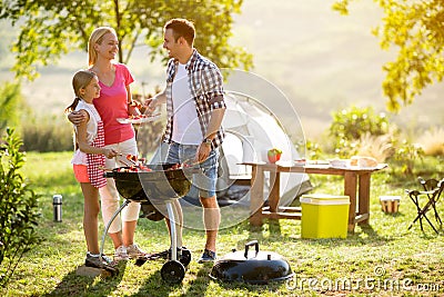 Smiling parent grilling meat with daughter Stock Photo