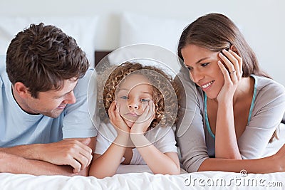 Smiling parents lying on a bed with their son Stock Photo