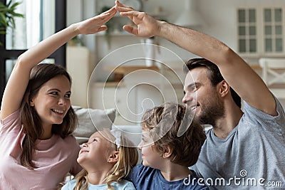 Smiling parents sitting with kids, making roof gesture with hands Stock Photo