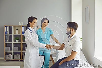 Smiling patient gives a handshake to his doctor at the clinic after the examination. Stock Photo