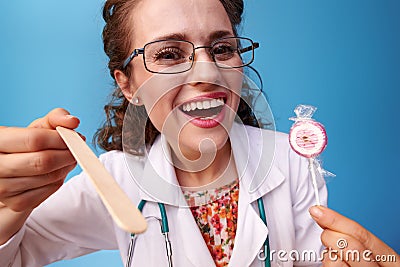 Pediatrist doctor with lollipop using spatula to examine throat Stock Photo