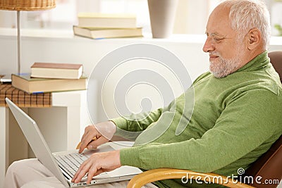 Smiling pensioner using laptop computer Stock Photo