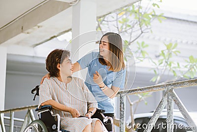 Smiling physiotherapist taking care of the happy senior patient in wheelchair Stock Photo