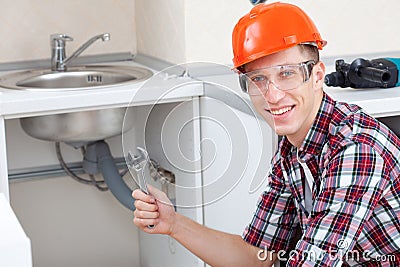 Smiling plumber near the kitchen sink Stock Photo