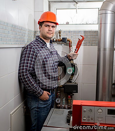 Smiling plumber posing with pliers at boiler room Stock Photo